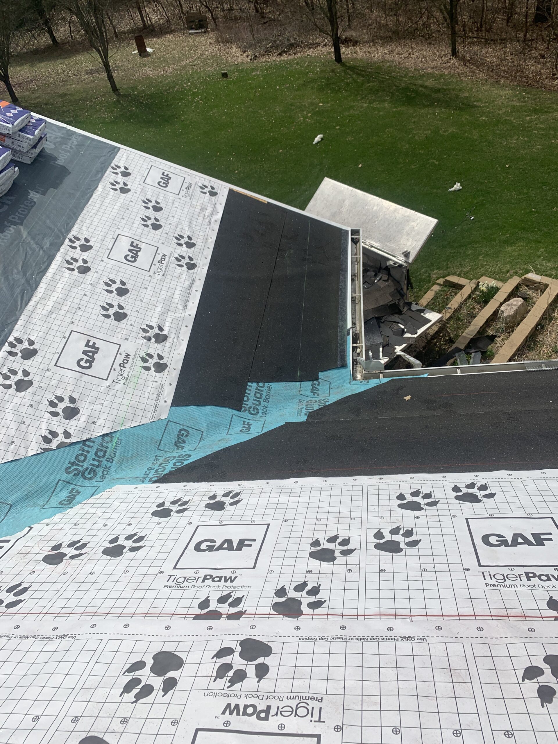 Crew installing new asphalt shingle roof on a single-family home in Gobles, MI during springtime